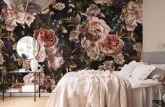 a bedroom with floral wallpaper and a bed in front of a mirror on the wall