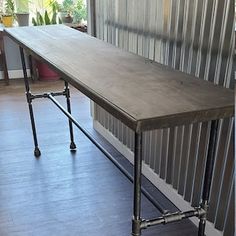 a long table sitting on top of a hard wood floor next to a metal fence