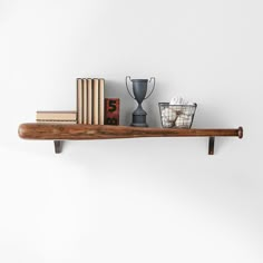 a wooden shelf with books, vases and other items on it against a white wall