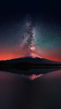 the night sky is reflected in water with a mountain in the background