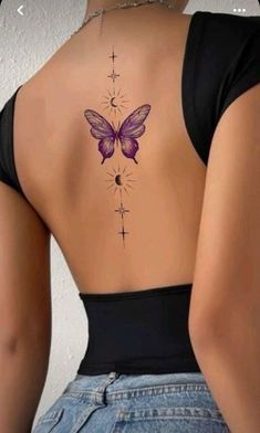 the back of a woman's neck with a purple butterfly tattoo on her lower back