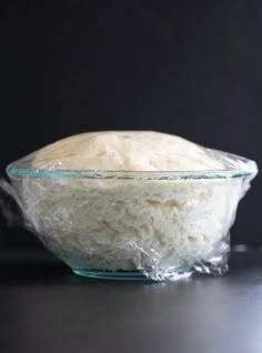 a glass bowl filled with rice sitting on top of a table next to a black wall