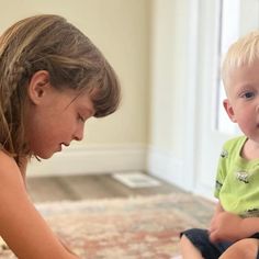 a woman is playing with a baby on the floor