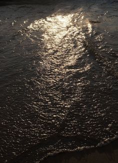 the sun shines brightly on the water as it reflects off the sand at the beach