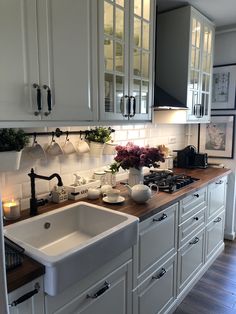 a kitchen with white cabinets and wooden counter tops, including a large farmhouse style sink