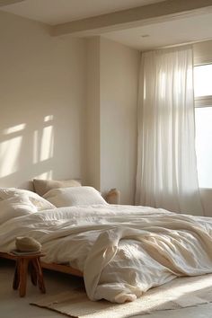 an unmade bed with white sheets and pillows in a bedroom next to a window