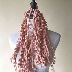 a mannequin wearing a pink scarf with pom - poms on it