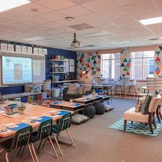 a classroom with tables, chairs and a projector screen