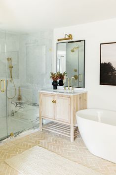 a bathroom with a tub, sink and large mirror on the wall next to it