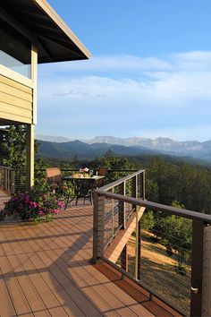 a wooden deck with chairs and table overlooking mountains