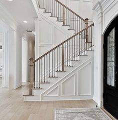 a white staircase with black door and rug on the floor in front of it is an entry way