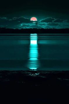 the moon is shining brightly in the night sky over water with dark clouds and trees