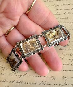 This elegant bracelet showcases cameo picture panels, crafted from mother of pearl. Each panel is framed by a detailed border adorned with marcasite stones. The bracelet is made from 800 silver, a metal commonly used in antique European jewellery, slightly less pure than sterling silver. Overall this piece is in very good antique condition, with no signs of damage and no missing marcasite. The clasp is in well working order and the bracelet features a safety chain for peace of mind. It measures Antique Silver Cabochon Bracelets, Silver Cameo Bracelet For Gifts, Vintage Silver Cameo Bracelet, Vintage Intaglio Bracelet For Gift, European Jewelry, Antique Bracelets, Safety Chain, Elegant Bracelet, Chain Link Bracelet