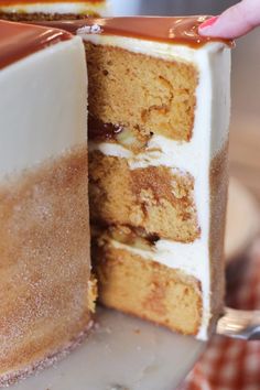 a person is holding a piece of cake in front of the other half of the cake