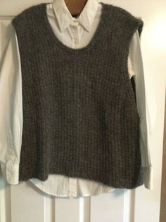 a gray sweater vest hanging on a white door with a button down shirt underneath it