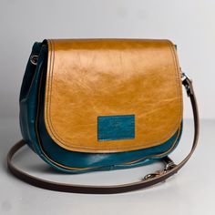 Our Everyday Collection of handbags reflects our task, offering tried + true styles + combinations that are timeless + classic. Colors + sizes to keep up with your effortless style + quality that holds up to your everyday adventures. The Mini "E" or mini Esther is our newest take on a fun flapped cross body. Perfected with a pocket on the inside + on the outside and the perfectly sweet size for your next adventure. Available in Black + Rocky and Butter + Turquoise. Dimensions: 9" x 9" x 2.5" Inc Modern Turquoise Bag For Everyday Use, Turquoise Leather Everyday Shoulder Bag, Turquoise Shoulder Bag For Everyday Use, Blue Travel Saddle Bag, Turquoise Leather Shoulder Bag For Travel, Turquoise Bag With Detachable Strap For Everyday Use, Turquoise Bags With Detachable Strap For Daily Use, Turquoise Bags With Leather Handles For Everyday Use, Turquoise Rectangular Shoulder Bag For Everyday