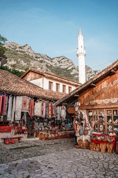 an outdoor market with lots of items on display and mountains in the backgroud