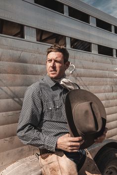 a man standing in front of a trailer holding a hat