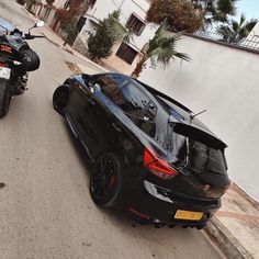 a black car parked on the side of a road next to a motor bike and motorcycle