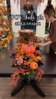 a woman is decorating a table with pumpkins and other autumn decorations on it