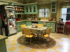 a kitchen with green cabinets and yellow chairs around a table in the center of the room