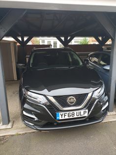 two cars are parked in a carport with one is black and the other is gray