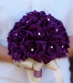 a bridal bouquet with purple flowers and pearls