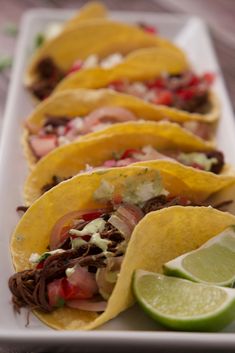 several tacos are lined up on a white plate