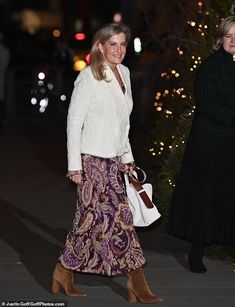 two women are walking down the street at night, one is carrying a white purse