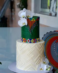 a multi - tiered cake with white flowers on the top and green icing