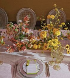 the table is set with yellow and pink flowers in vases, silverware, and napkins