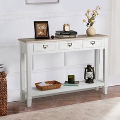 a white console table with two drawers and a basket on the floor next to it