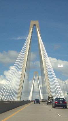 cars are driving on the road in front of a tall bridge