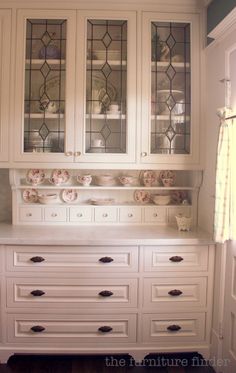 a white china cabinet with glass doors and drawers