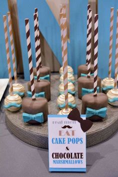 there are many cake pops with chocolate and candy sticks on the table in front of them