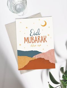 an eid mubarak greeting card on top of a table next to a plant