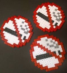 three red, white and black pixelated coasters on top of a gray table