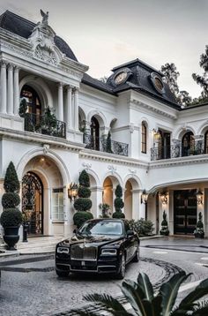 a black car is parked in front of a mansion