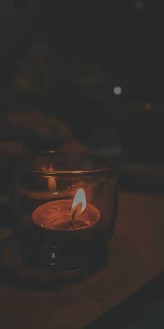 a lit candle in a glass bowl on a table