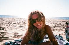 a woman laying on top of a beach next to a bottle