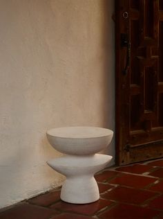 a white bowl sitting on top of a brick floor next to a door and doorway