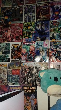 a teddy bear sitting next to a wall covered in comic books