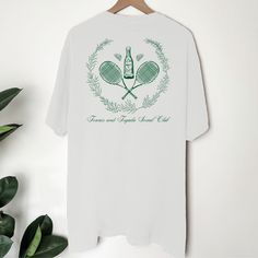 a t - shirt with two tennis rackets in the shape of a heart on a hanger