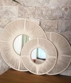 two white wicker mirrors sitting on top of a wooden table next to a brick wall