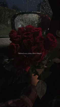 a bouquet of red roses sitting in front of a window with the words behind it