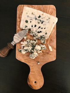 a wooden cutting board topped with cheese and a knife