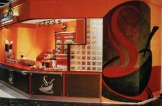 the interior of a coffee shop with an orange and black mural on the wall behind it