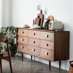 a wooden dresser sitting next to a potted plant