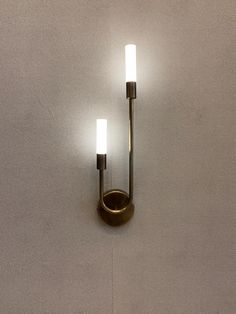 two lights that are on the wall next to each other in a room with white walls