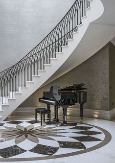 a grand piano sitting in front of a stair case next to a black and white piano